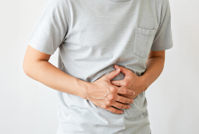 両手で胃をおさえる男性